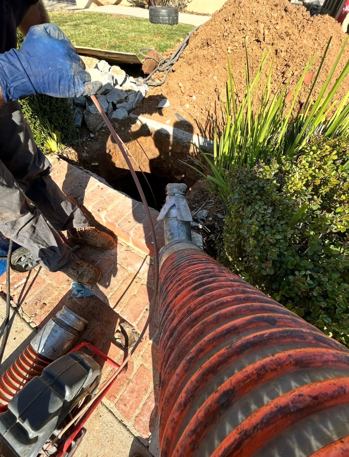 Technician running a hydro-jetting hose into a sewer cleanout