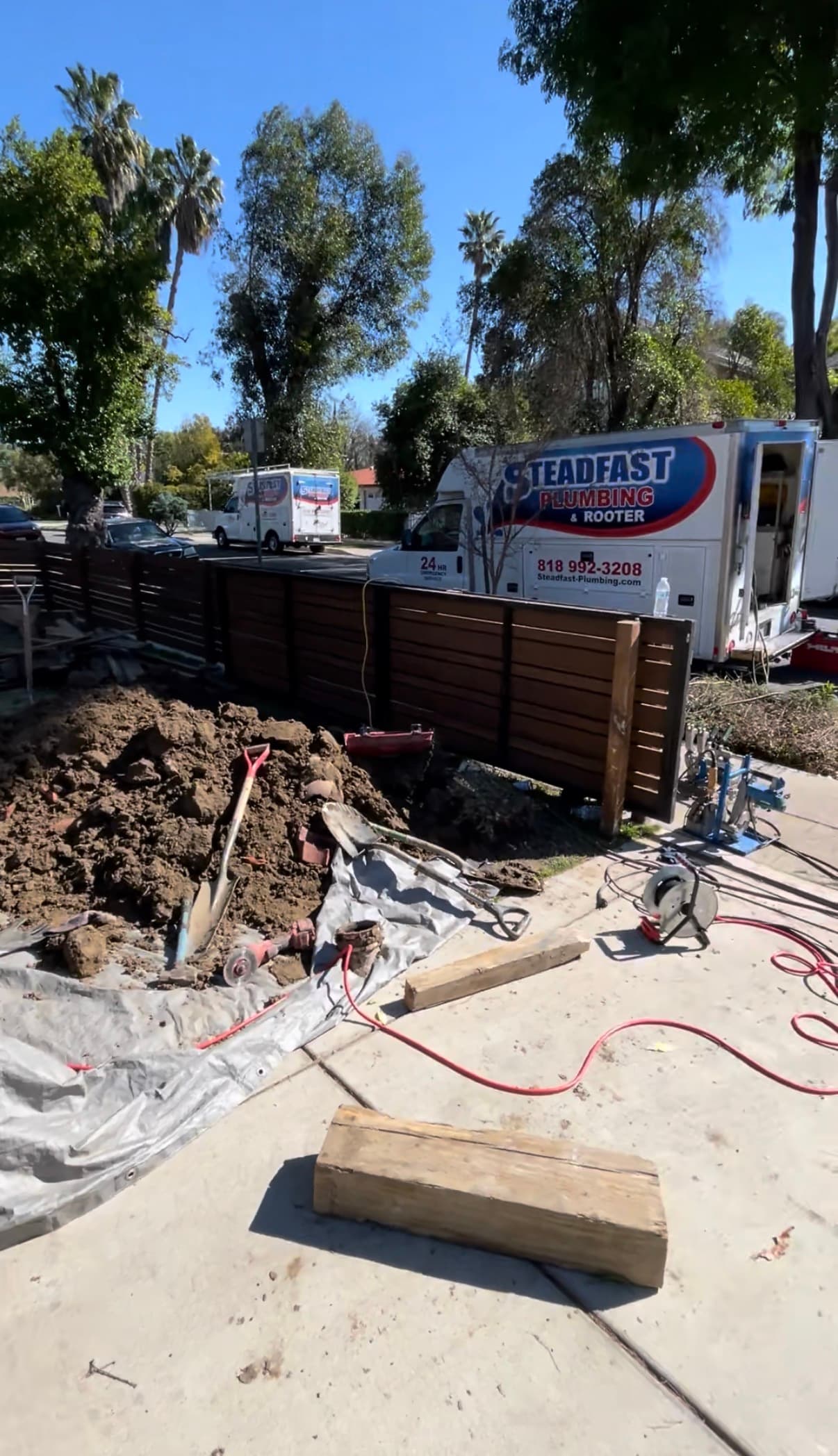 Two branded Steadfast Plumbing box trucks at a residential job site